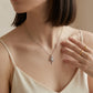 Model wearing round diamond intertwined swirl solitaire pendant necklace with white top.