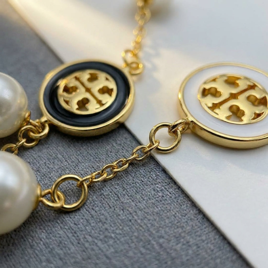 Close-up of the Tory Burch bracelet highlighting the pearl luster and polished gold chain links