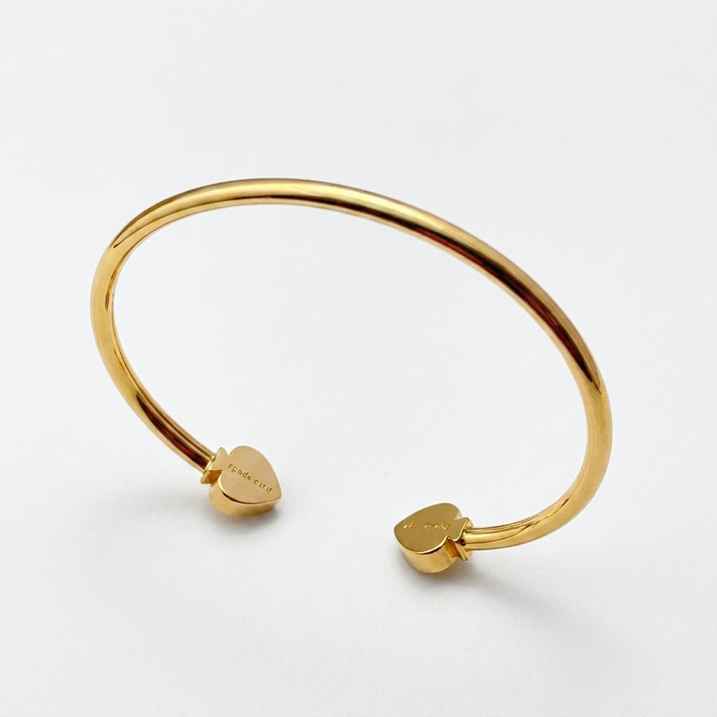 Detailed shot of the lobster clasp and the signature spade logo tag on the gold bracelet