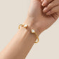 Model touches her hair wearing the New Classic Heart Gold Bracelet, capturing natural luster
