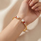 Macro detail of the vibrant red enamel and soft white pearls on the Kate Spade wisdom bracelet