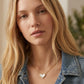 A model wearing the Kendra Scott Ari gold heart pendant necklace with a casual denim jacket to show hanging length