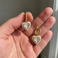 Hand-held size reference of the Ari Heart Huggie Earrings to show the delicate jewelry scale