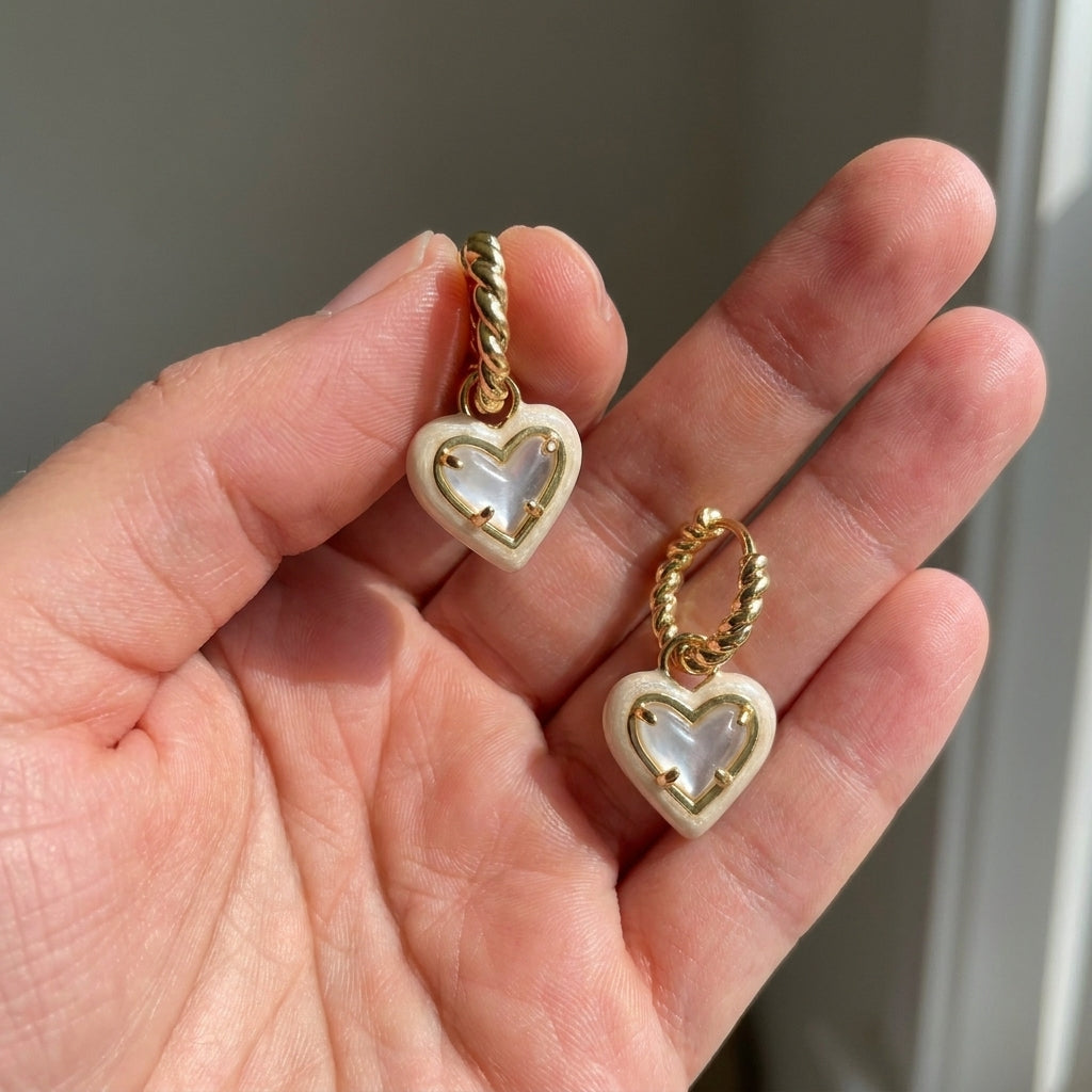 Hand-held size reference of the Ari Heart Huggie Earrings to show the delicate jewelry scale