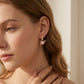 Side profile of a woman showcasing the romantic pink charm Kendra Scott Ari heart arrow earrings.