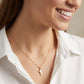 Close-up of a smiling model wearing the white and gold cross pendant necklace.