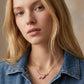 Model in a blue denim jacket wearing the gold Kendra Scott Ari heart arrow pendant necklace.