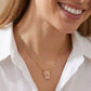 Smiling model wearing the gold Kendra Scott ballet slippers pendant necklace with a white blouse.