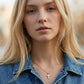 Blonde female model wearing the gold Kendra Scott cross pendant necklace.