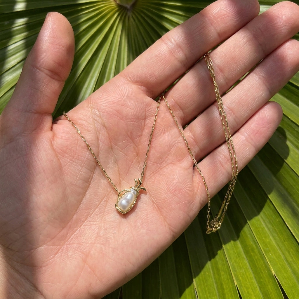 Hand-held size reference of the Kendra Scott gold Golf Necklace to show the delicate scale