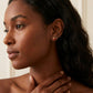 Model touches hair wearing Gold Ladybug Studs, capturing the golden sparkle in natural light