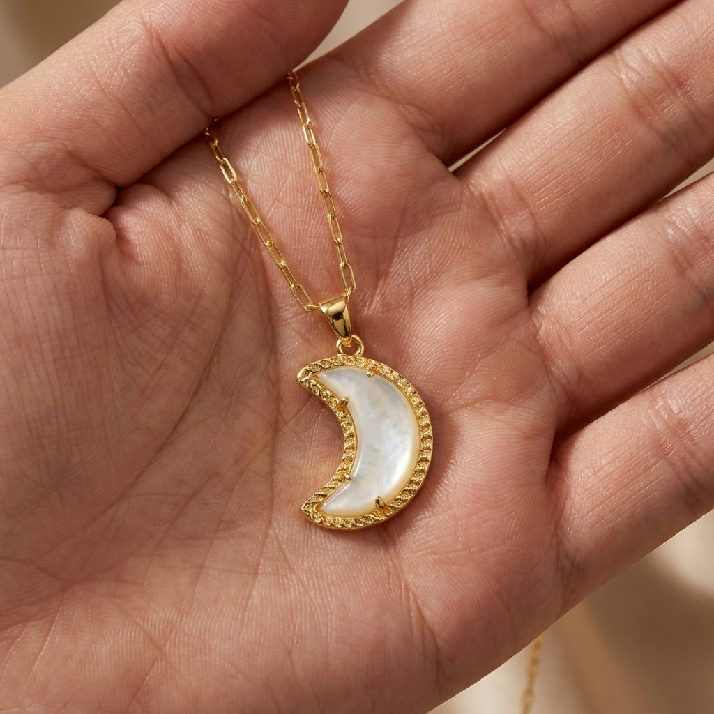 The Kendra Scott white mother of pearl crescent moon necklace placed in a hand for scale and texture reference.