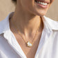Model wearing the Kendra Scott gold rabbit short pendant necklace with a white button-down shirt.