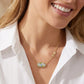 A model wearing the Kendra Scott x LoveShackFancy floral pendant necklace with a vintage bow to showcase styling and chain length.