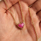 Hand holding the gold Kendra Scott Ari pink heart necklace to showcase the stone texture under natural sunlight