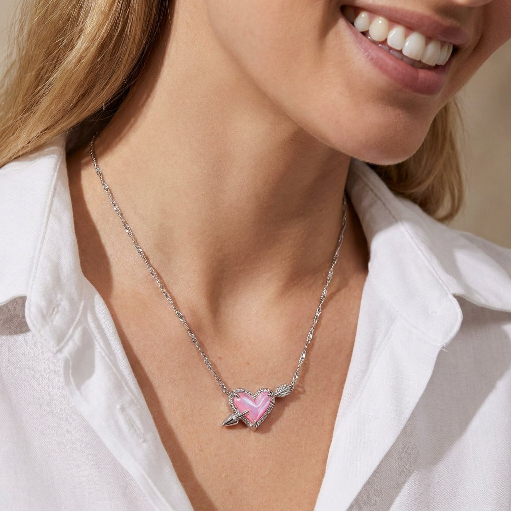 Close-up of a smiling model wearing the silver Kendra Scott Ari heart arrow necklace with a white blouse