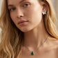 Model adjusts her hair wearing Kendra Scott Holiday Tree Necklace, capturing the festive shimmer