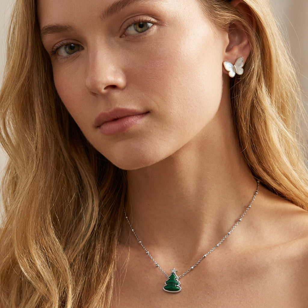 Model adjusts her hair wearing Kendra Scott Holiday Tree Necklace, capturing the festive shimmer