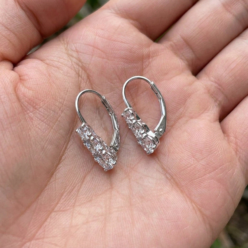 Hand holding lab grown diamond three stone past present future leverback earrings.