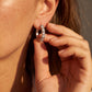 Close-up of model wearing lab grown diamond X cross cable wire huggie earrings.