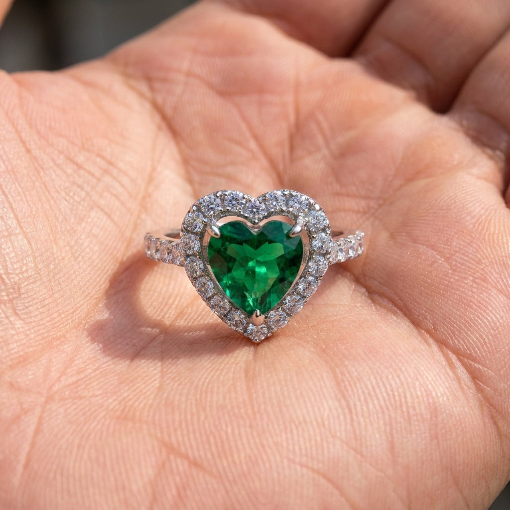 Handheld view under direct natural sunlight capturing a lab-grown heart-shaped emerald halo ring.