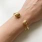 Gold bracelet on a wrist against a white background