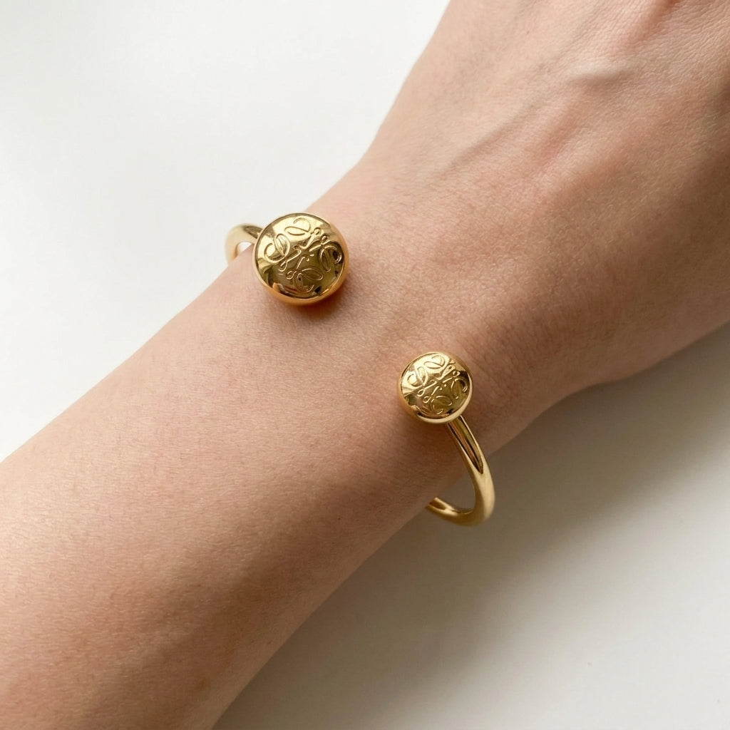 Gold bracelet on a wrist against a white background