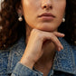 Model adjusts hair wearing Loewe Geometric Pearl Earrings, capturing the swaying luster