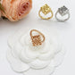 Three rings in gold, rose gold, and silver on a white flower with a pink rose.