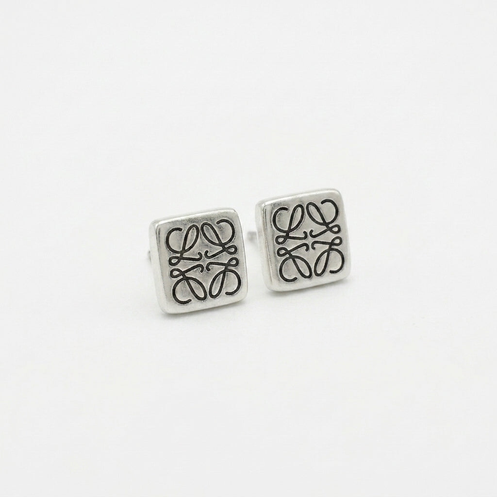 Macro detail of the silver square Anagram studs showing the precision polished edges