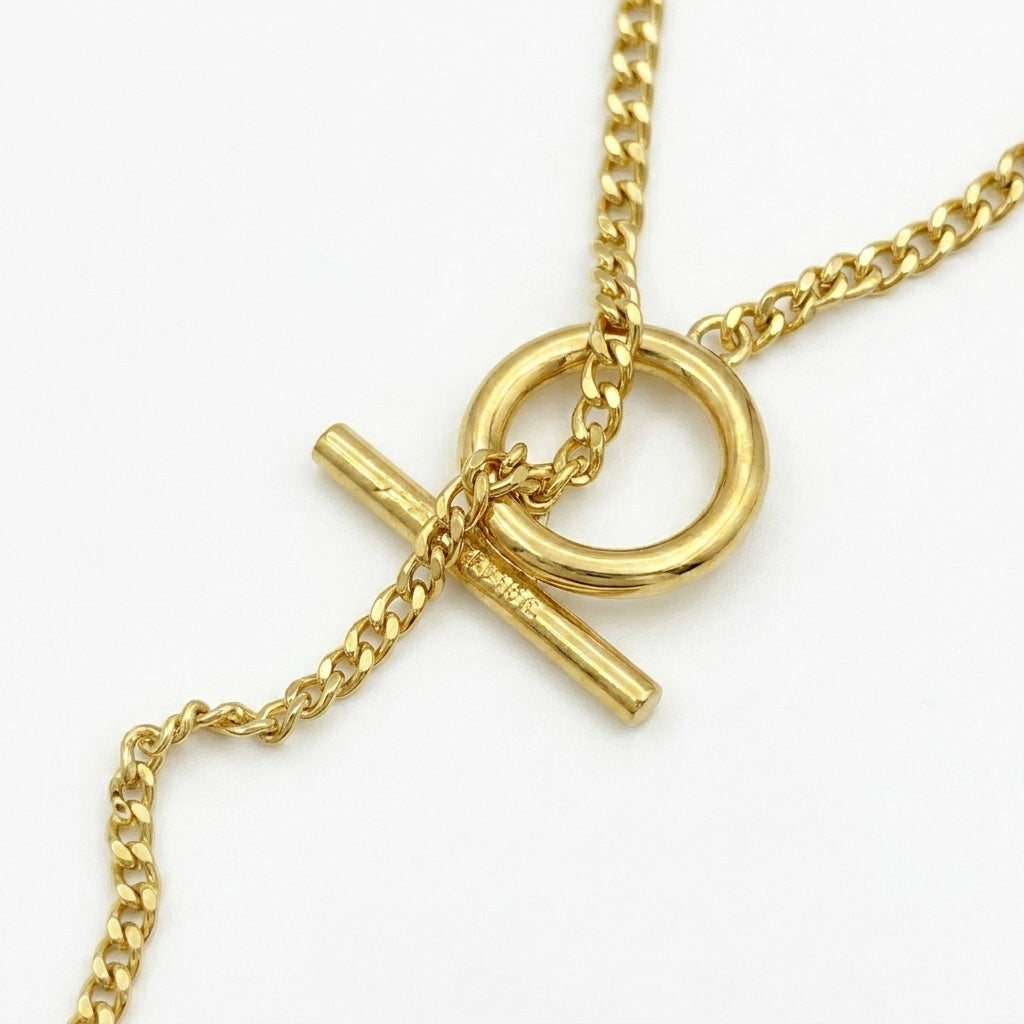 Macro detail of the silver toggle clasp and Anagram pendant showing the high-polish finish