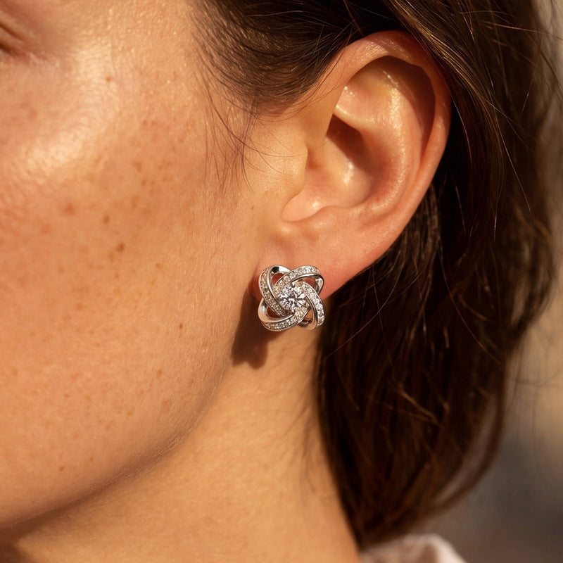 Model wearing love knot round cut lab grown diamond pavé halo stud earrings.
