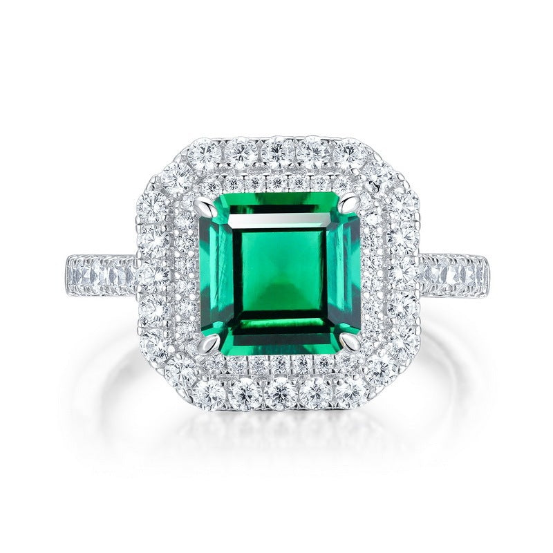 White background front view showcasing a luxury emerald-cut lab-created emerald double halo statement ring with a pave diamond band.