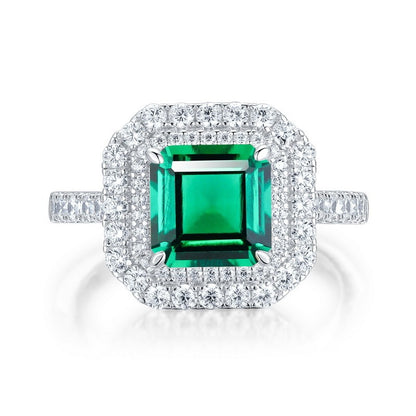 White background front view showcasing a luxury emerald-cut lab-created emerald double halo statement ring with a pave diamond band.