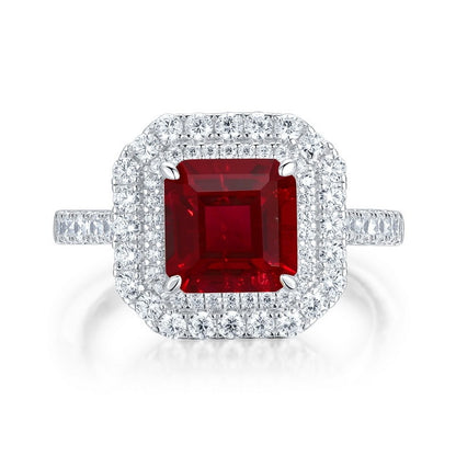 White background front view showcasing a luxury emerald-cut ruby double halo statement ring with a pave diamond band.
