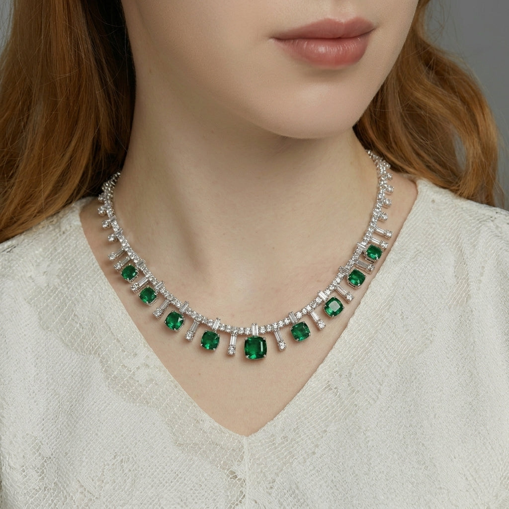Elegant model smiling and gesturing toward her cushion-cut emerald fringe necklace, lifestyle view.