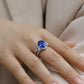 Side angle lifestyle shot of a model showcasing a luxury oval blue sapphire split-shank ring on her finger.