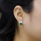 Side view of a model wearing the short stud side of luxury oval-cut emerald asymmetric leaf earrings.