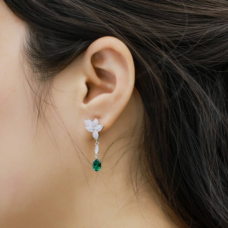 Side profile view of a model wearing the long linear drop side of classic emerald mismatched leaf earrings.