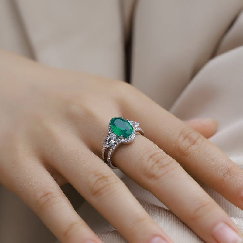 Side angle lifestyle shot of a model showcasing a luxury oval emerald split-shank ring on her finger.
