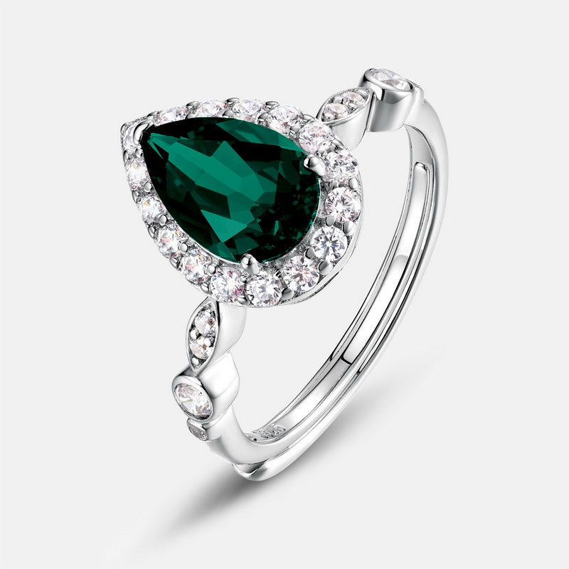 Studio profile view of a luxury pear-shaped lab-grown emerald halo engagement ring with a custom micro-pave diamond band.