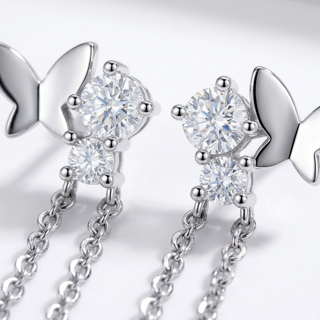 Micro profile view showing the sterling silver butterfly wing, brilliant round moissanite setting, and delicate tassel chains.