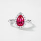 White background front view showcasing a luxury pear-shaped lab-grown ruby halo engagement ring with a pave diamond band.