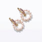 High-angle studio view of luxury pearl circle hoop earrings with shimmering crystal hugging posts and dangling logo charms.