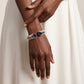 Hand wearing a silver bracelet with blue gemstones against a neutral background