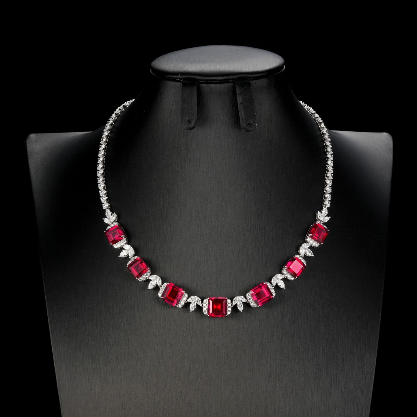 Front product view of a luxury square-cut ruby statement necklace displayed on a premium black mannequin bust.