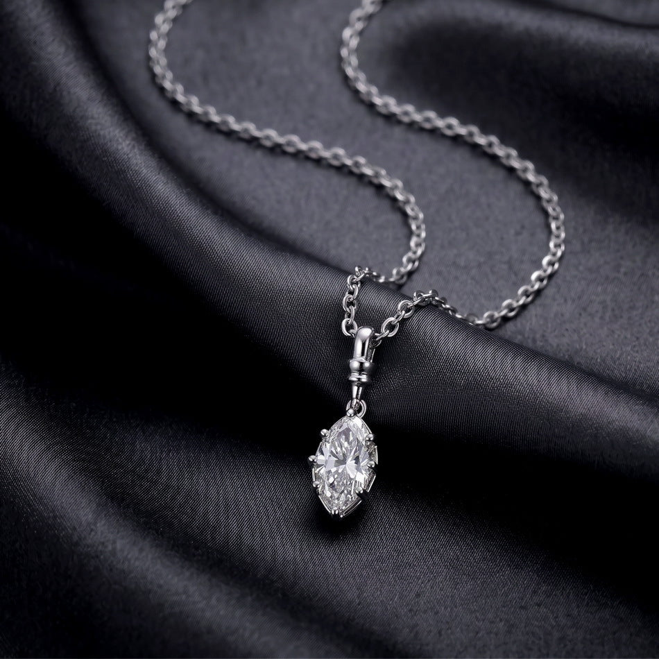 Perspective view of marquise cut lab diamond bezel pendant necklace resting on black silk fabric.