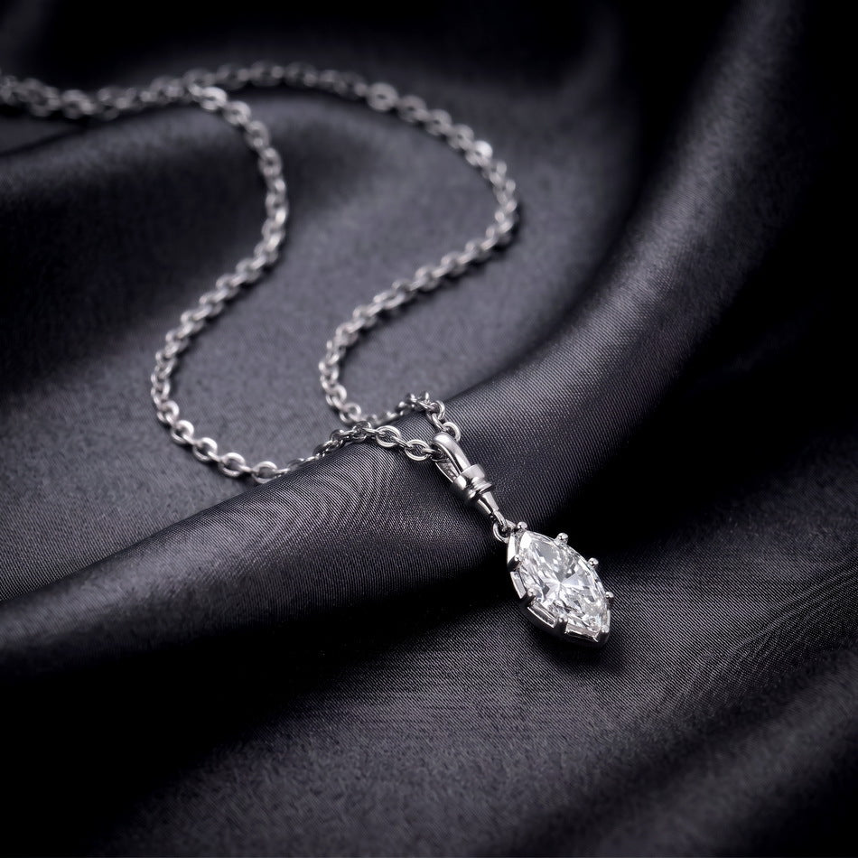 Marquise cut lab diamond solitaire bezel drop pendant with filigree bail on dark silk background.