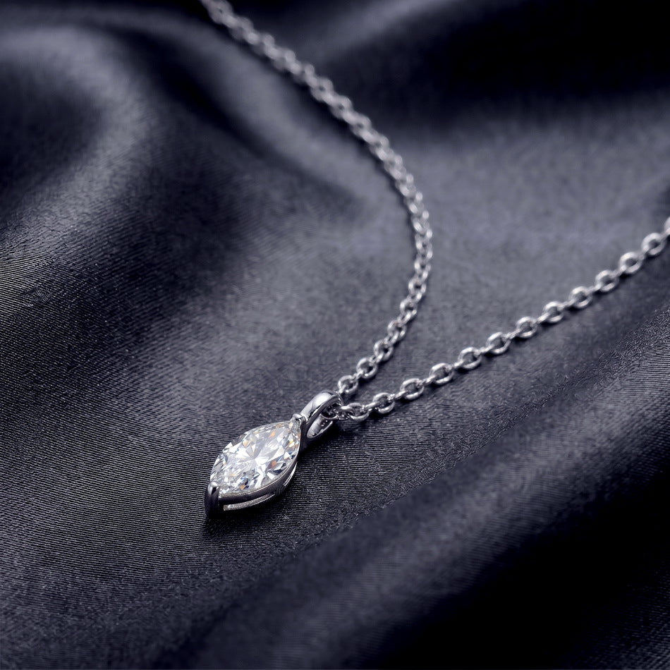 Side profile shot of marquise cut lab diamond solitaire pendant necklace resting on dark silk.