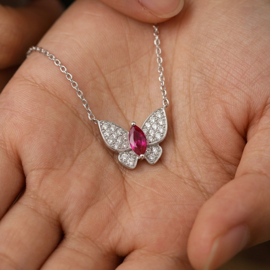 Real-life lifestyle hand view of a model holding a luxury marquise-cut ruby butterfly pendant necklace in her palm.